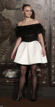 Lily-Rose Depp with a white skirt and black tights