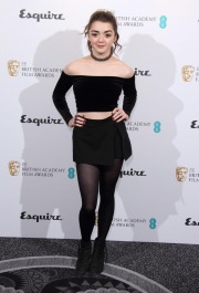 Maisie Williams wearing a black dress and tights